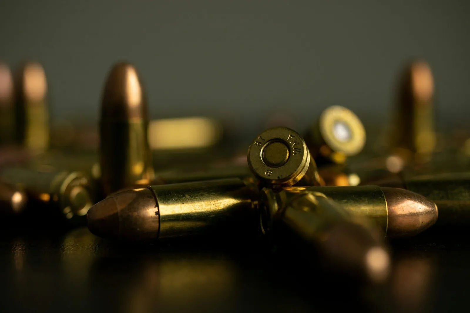 A silver and gold metal cartridge on a wooden surface