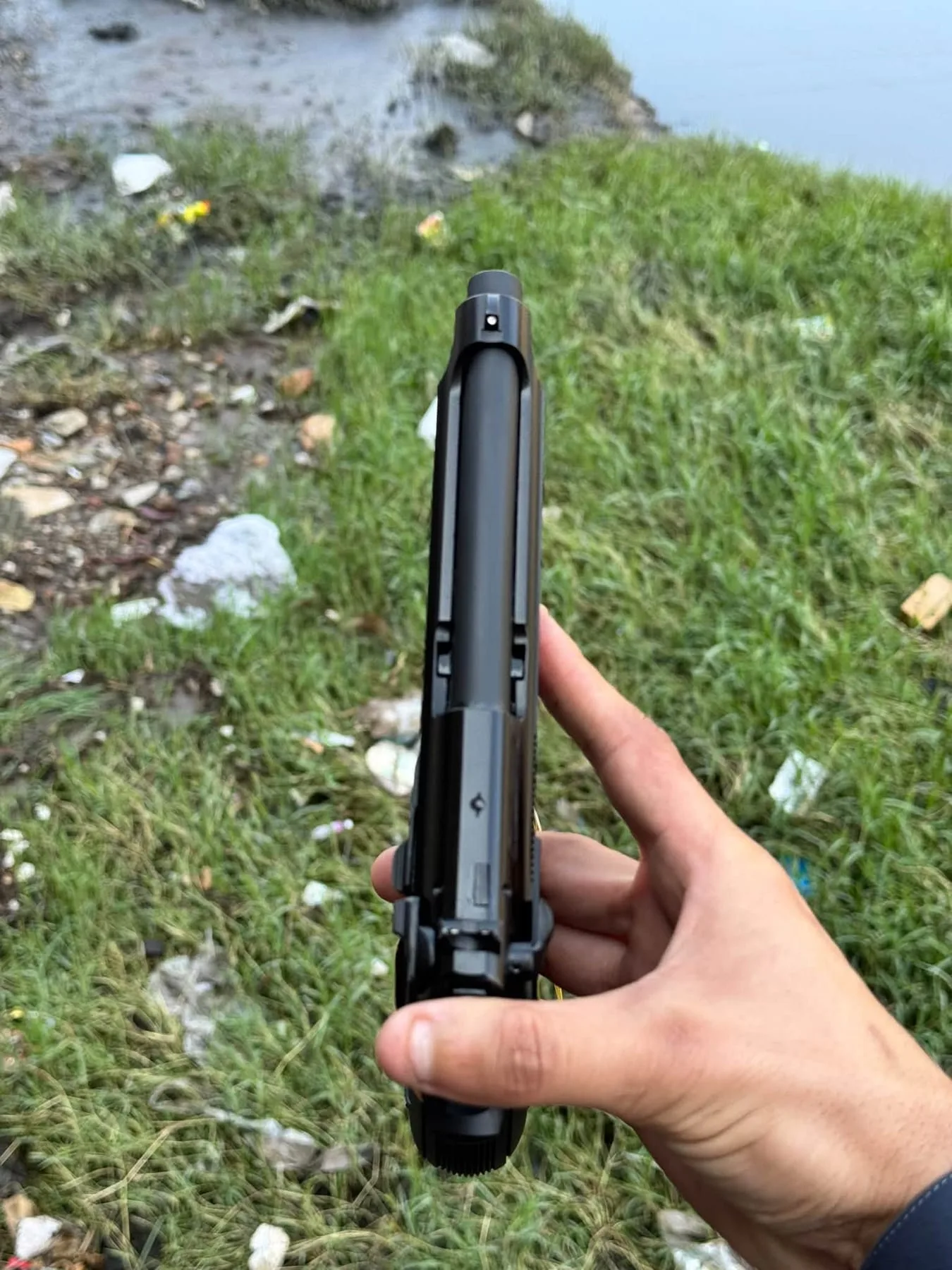 A black pistol held up against grass