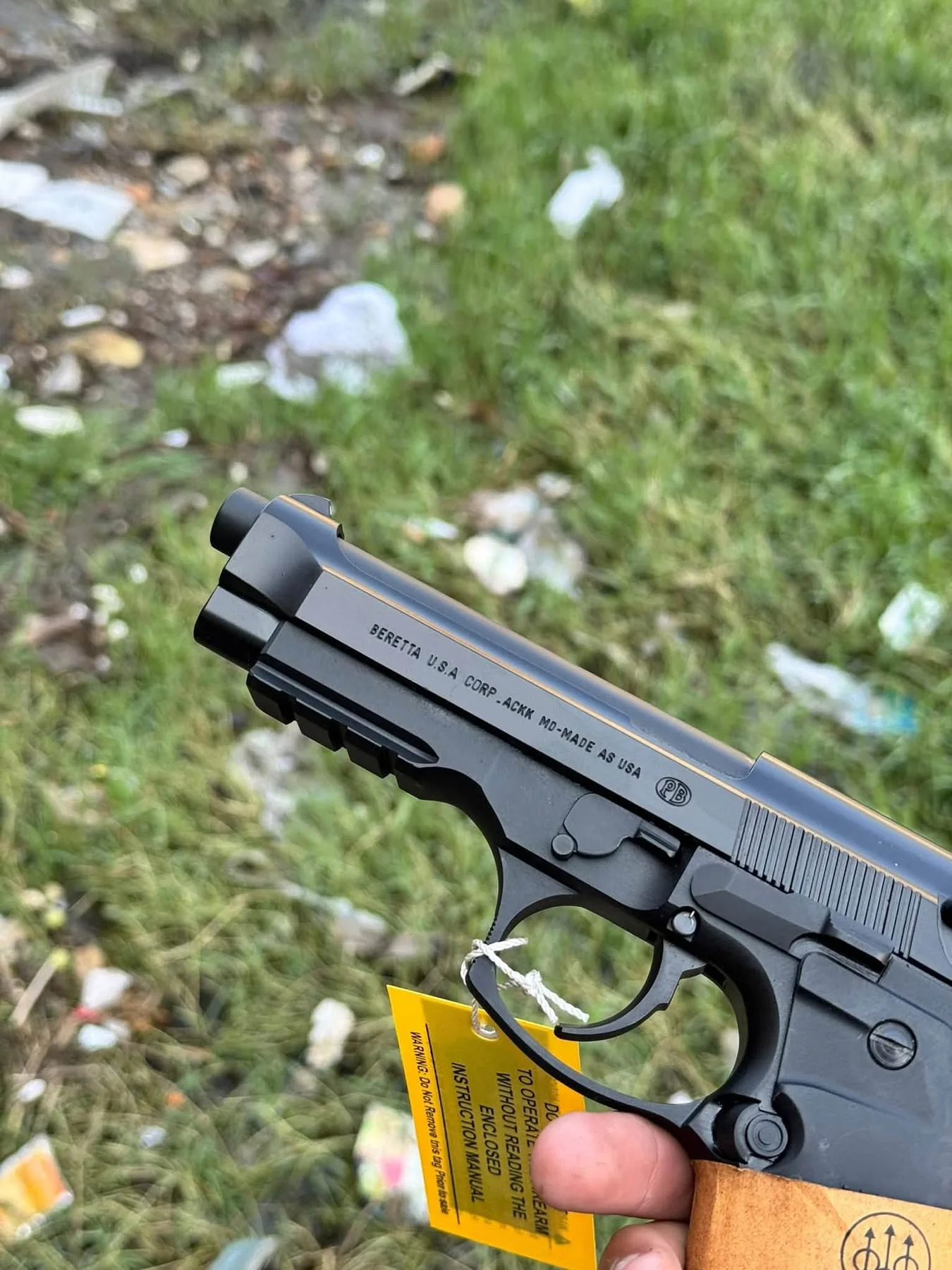 A Beretta-pattern 9mm pistol with its tag, held in hand