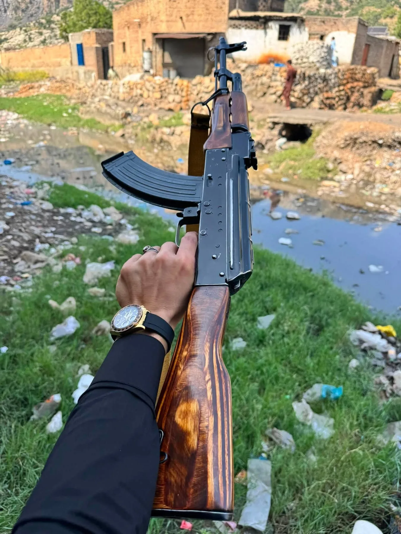 An AK-pattern rifle with wooden furniture, held outdoors