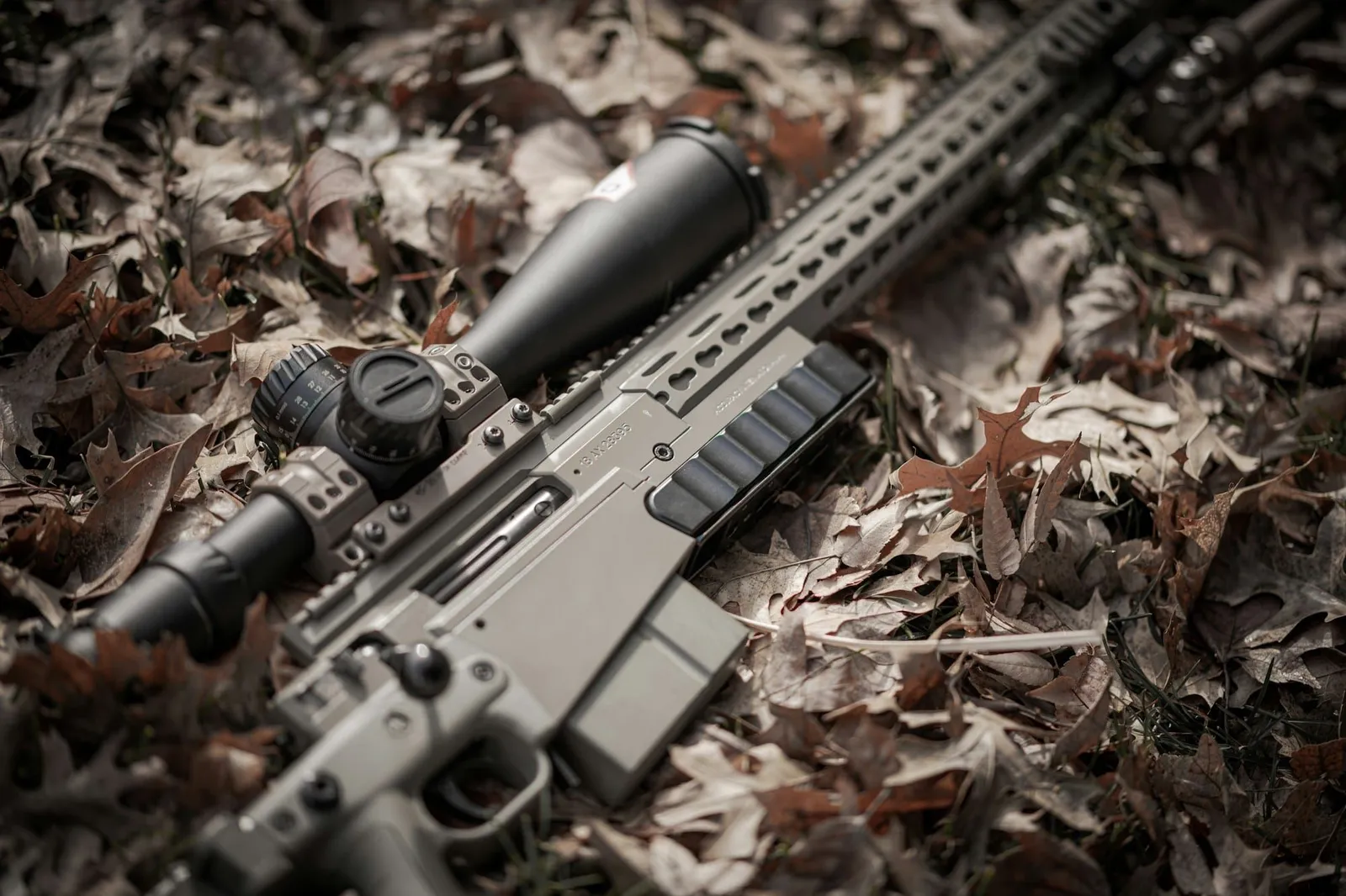 A rifle fitted with an optical sight, laid on the ground
