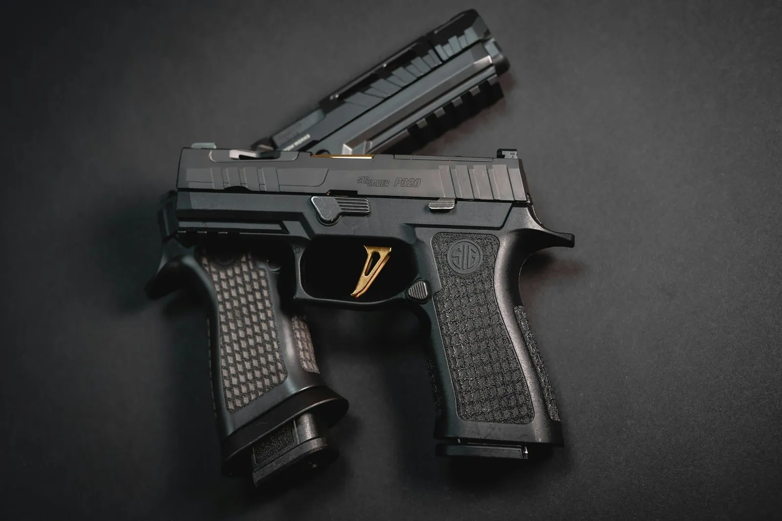 A close-up of a semi-automatic pistol on a black surface